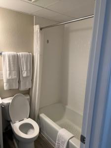 a bathroom with a toilet and a bath tub with towels at Dunes Suites Oceanfront in Ocean City