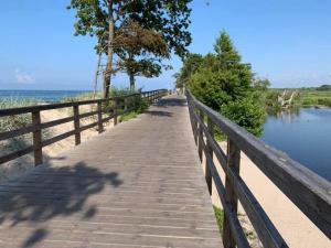 a wooden boardwalk next to the water with a fence at Comfortable cottage for 4 people, Ustronie Morskie in Ustronie Morskie