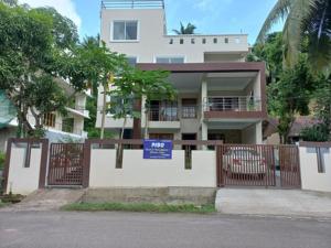 una gran casa blanca con un cartel azul delante de ella en Pibo Homestay, en Port Blair