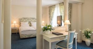 una camera d'albergo con letto e scrivania, un letto e una camera da letto di Victor's Residenz-Hotel Saarbrücken a Saarbrücken