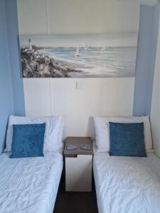 a room with two beds with blue pillows and a table at Ocean view in Paignton +26 photos