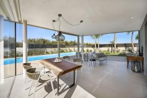 a dining room with a table and chairs and a pool at Villas Don Serafino in Marina di Ragusa