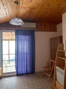 een kamer met een blauw gordijn en een raam bij Ξυλινο σπίτι δίπλα στην θάλασσα in Kineta