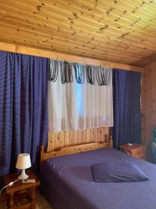 een slaapkamer met een blauw bed en blauwe gordijnen bij Ξυλινο σπίτι δίπλα στην θάλασσα in Kineta