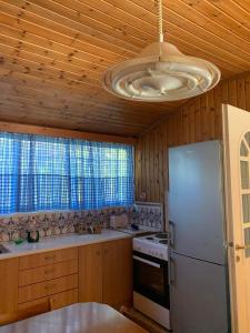 een keuken met een witte koelkast en een plafond bij Ξυλινο σπίτι δίπλα στην θάλασσα in Kineta