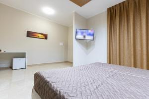 1 dormitorio con 1 cama y TV en la pared en Agri-Resort Luxury Farm, en Marigliano