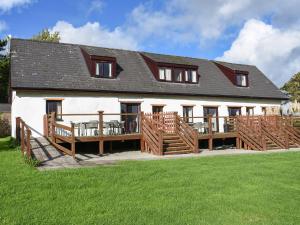 a large white building with a deck and a house at Holly Cottage in Beaworthy