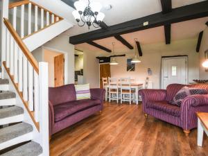 a living room with two purple couches and a dining room at Holly Cottage in Beaworthy