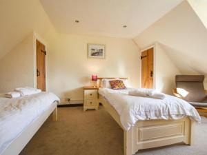 a bedroom with two beds and a chair at Holly Cottage in Beaworthy