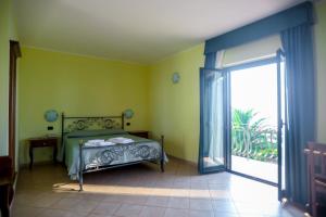 Schlafzimmer mit einem Bett und einer Glasschiebetür in der Unterkunft Villaggio Hotel Lido San Giuseppe in Briatico