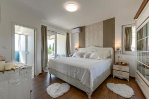 a bedroom with a white bed and a balcony at Villa Azzuro with jacuzzi and pool in Sveti Filip i Jakov +93 photos