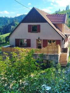 uma casa com um alpendre e uma cerca em frente em L'Estive, gîte à la ferme en montagne em Eschbach-au-Val