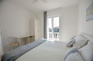 - une chambre blanche avec un grand lit et une fenêtre dans l'établissement Apartments and Rooms On the Beach, à Vodice