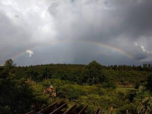 a rainbow in the sky over a field with trees at Bela Vista Casa Serrana, Golpe de Agua in Los Reartes