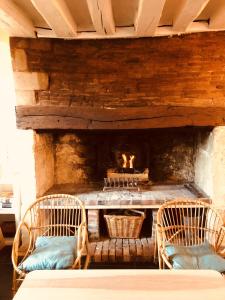 einen Tisch mit 3 Stühlen und einen Kamin in der Unterkunft Maison de famille du 17ème siècle 
