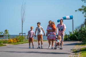 een familie die over een weg loopt op rolschaatsen bij EuroParcs Enkhuizer Strand in Enkhuizen