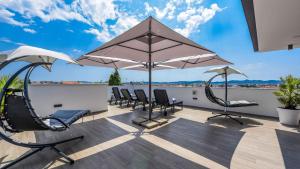 a patio with chairs and umbrellas on a deck at Rooftop heated pool Villa Jelena in Zadar