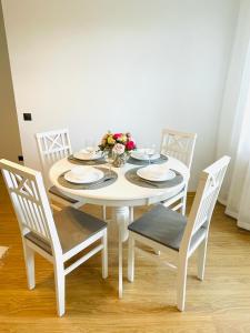 a white dining room table with four chairs and a white table and chairsktop at Keskuse apartment with a balcony in Haapsalu