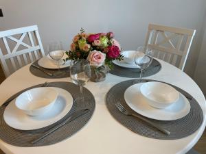 a table with plates and wine glasses and a bouquet of flowers at Keskuse apartment with a balcony in Haapsalu