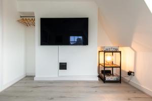 a room with a white wall with a television on the wall at Newly Renovated Central One-Bedroom, 99 Steps to the Sea in Brighton & Hove