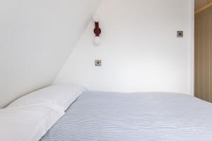 een wit bed met witte kussens erop bij Newly Renovated Central One-Bedroom, 99 Steps to the Sea in Brighton & Hove