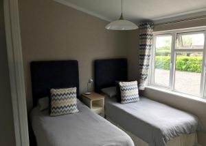 two beds in a room with two windows at Larkrise Farm Lodges in Babcary