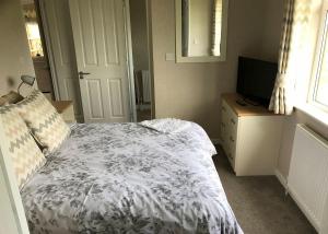 a bedroom with a bed and a television on a dresser at Larkrise Farm Lodges in Babcary