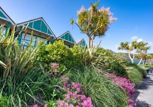ein Haus mit Palmen und Blumen davor in der Unterkunft Sea Breeze in Newton