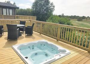 a hot tub on a deck with a table and chairs at Kingswood Golf Lodges in Thorne