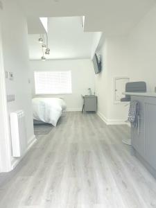 Habitación blanca con cama y suelo de madera. en The Bay Studio 2 - Broadstairs en Broadstairs