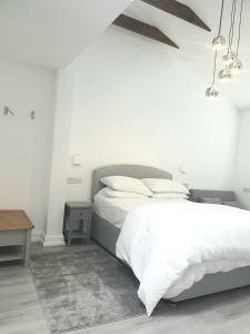 a white bedroom with a bed and a table at The Bay Studio 2 - Broadstairs in Broadstairs