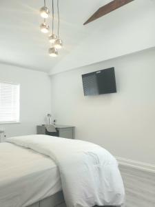 a white bedroom with a bed with a tv on the wall at The Bay Studio 2 - Broadstairs in Broadstairs