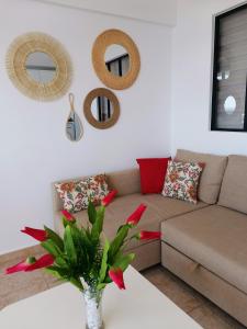 濱海帕爾姆的住宿－Palm-Mar Appartement Celeste 250m de l'ocean vue mer panoramique，客厅配有沙发和红色鲜花桌