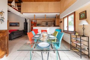 uma sala de jantar com uma mesa de vidro e cadeiras coloridas em Grande maison pour 10 avec piscine a Sarzeau em Sarzeau