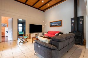 a living room with a couch and a tv at Grande maison pour 10 avec piscine à Sarzeau in Sarzeau