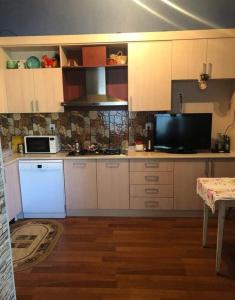 a kitchen with white cabinets and a microwave and a television at дом в новханах у моря in Baku