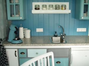a kitchen with blue walls and a sink and a chair at Noordwester 45 in Den Burg