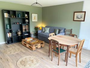 ein Wohnzimmer mit einem Tisch und einem blauen Sofa in der Unterkunft La Topaze - Etretat in Étretat