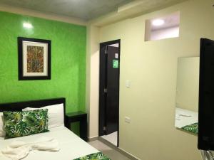 Dormitorio verde con cama y espejo en Ayenda Hotel Ecosuite Quibdó en Quibdó