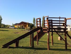 a wooden playground with a slide and a chair at Cabañas Mina Clavero La Amelia in Mina Clavero +3 photos