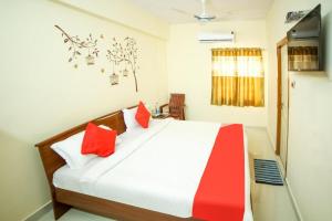 1 dormitorio con 1 cama con almohadas rojas y blancas en Nandas Grand, en Nellore