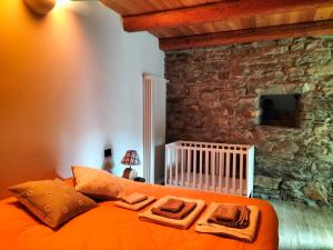 a bedroom with an orange bed and a stone wall at Baita del noce in Mollia