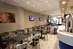 a restaurant with tables and chairs and televisions at Hôtel Cecyl Reims Centre in Reims