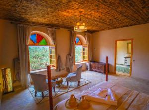 a bedroom with a bed and chairs and stained glass windows at Kasbah Hnini in Igdourane