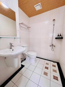 a white bathroom with a toilet and a sink at 安平六合居 六合館 in Tainan