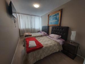 1 dormitorio con 2 camas y manta roja en Apartamento PARDO CCA, en Lima