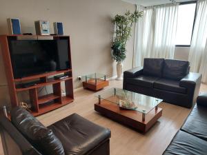 a living room with a leather couch and a television at Apartamento PARDO CCA in Lima
