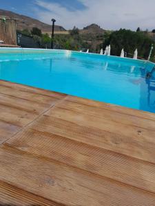 een groot blauw zwembad met een houten vloer bij Villa Parco Morello Primo Piano in Villarosa