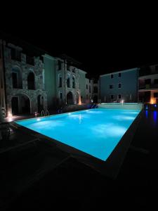 - une grande piscine bleue la nuit dans l'établissement Residence Valledoria 2 int 8, à Valledoria