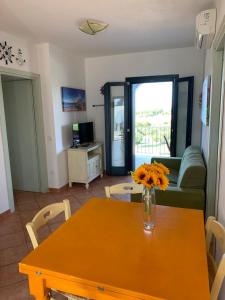 una sala de estar con una mesa con un jarrón de flores. en Residence Valledoria 2 int 8 en Valledoria